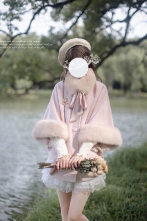 Pink Jirai Kei winter cape cloak with fluffy faux fur collar and white lace mini skirt, front full-body view on female model by lakeside