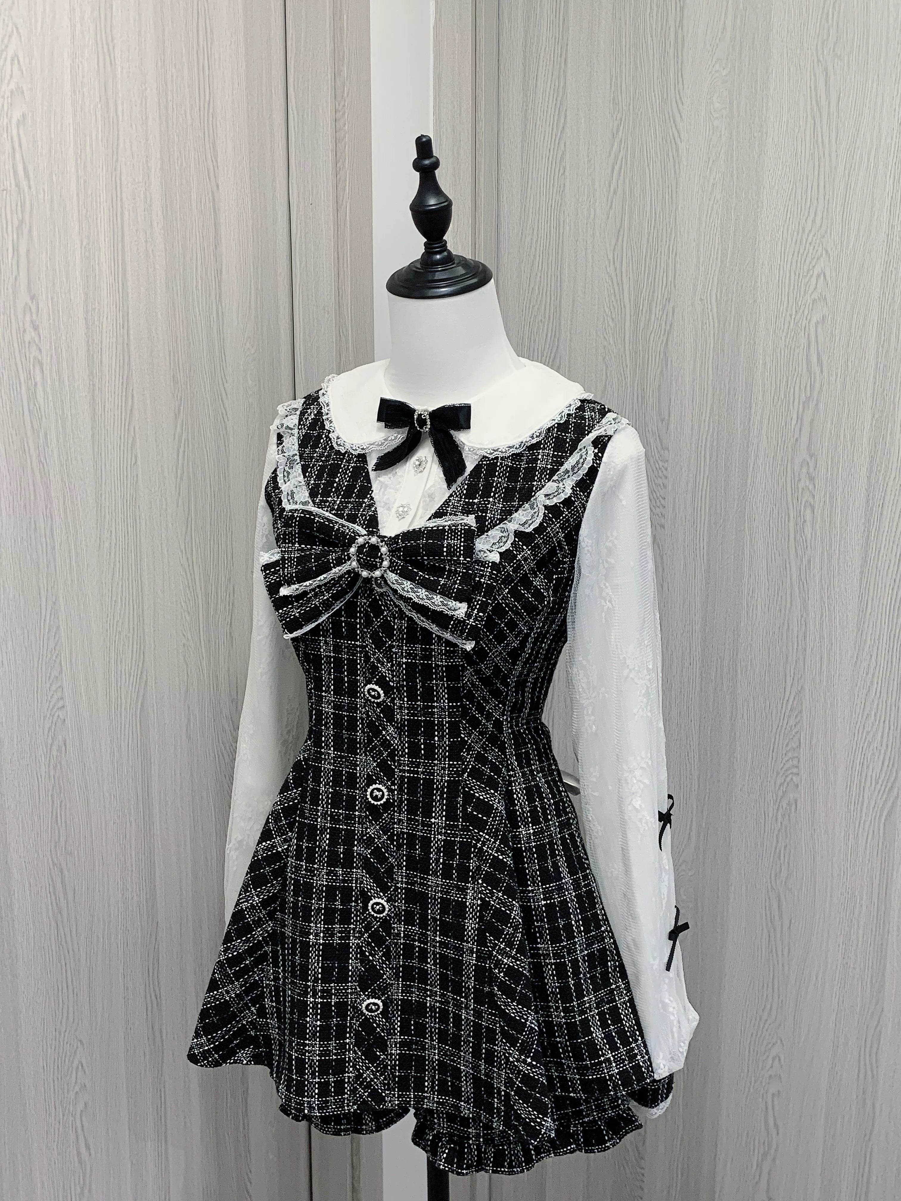 Full frontal view of two-piece Jirai Kei outfit showing plaid dress with lace Peter Pan collar, centered velvet bow tie, button row, and coordinating shorts with ruffle hem