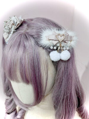 Beige ryousangata pom-pom hair clip with heart pearl charm and white fluffy pom-poms on mannequin head with light purple curly bangs, jirai kei lolita hair accessory left side view