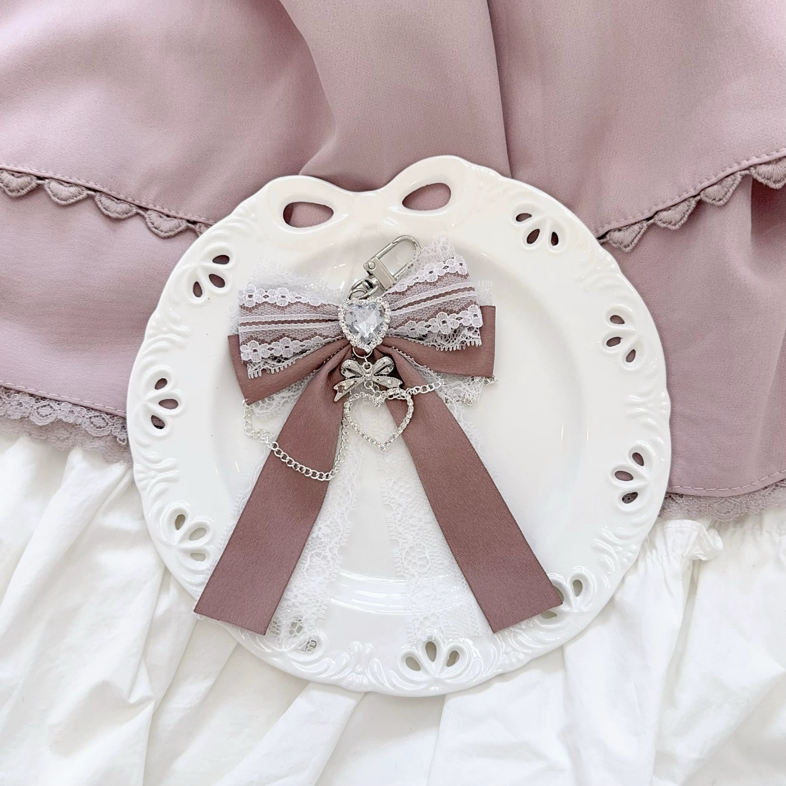 Taupe ribbon Ryousangata bow bag pendant with heart rhinestone and lace trim on decorative plate - overhead view of chain charm details for Jirai Kei accessory