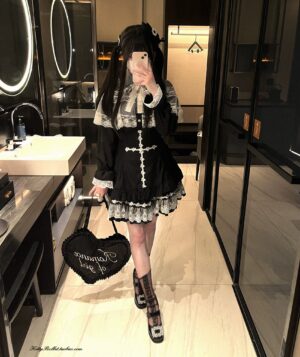 Side profile full-body view of gothic lace cape blouse with lace-trimmed collar and cuffs, worn with heart-shaped handbag in bathroom mirror