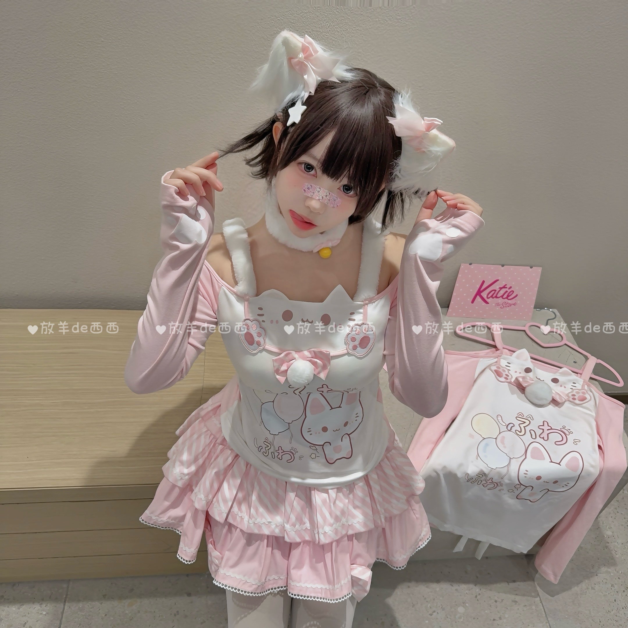 Cat-themed off-shoulder two-piece set with cute neckline design and paw-print embroidery details, front half-body product display on wooden table with top hung on hanger showing construction quality