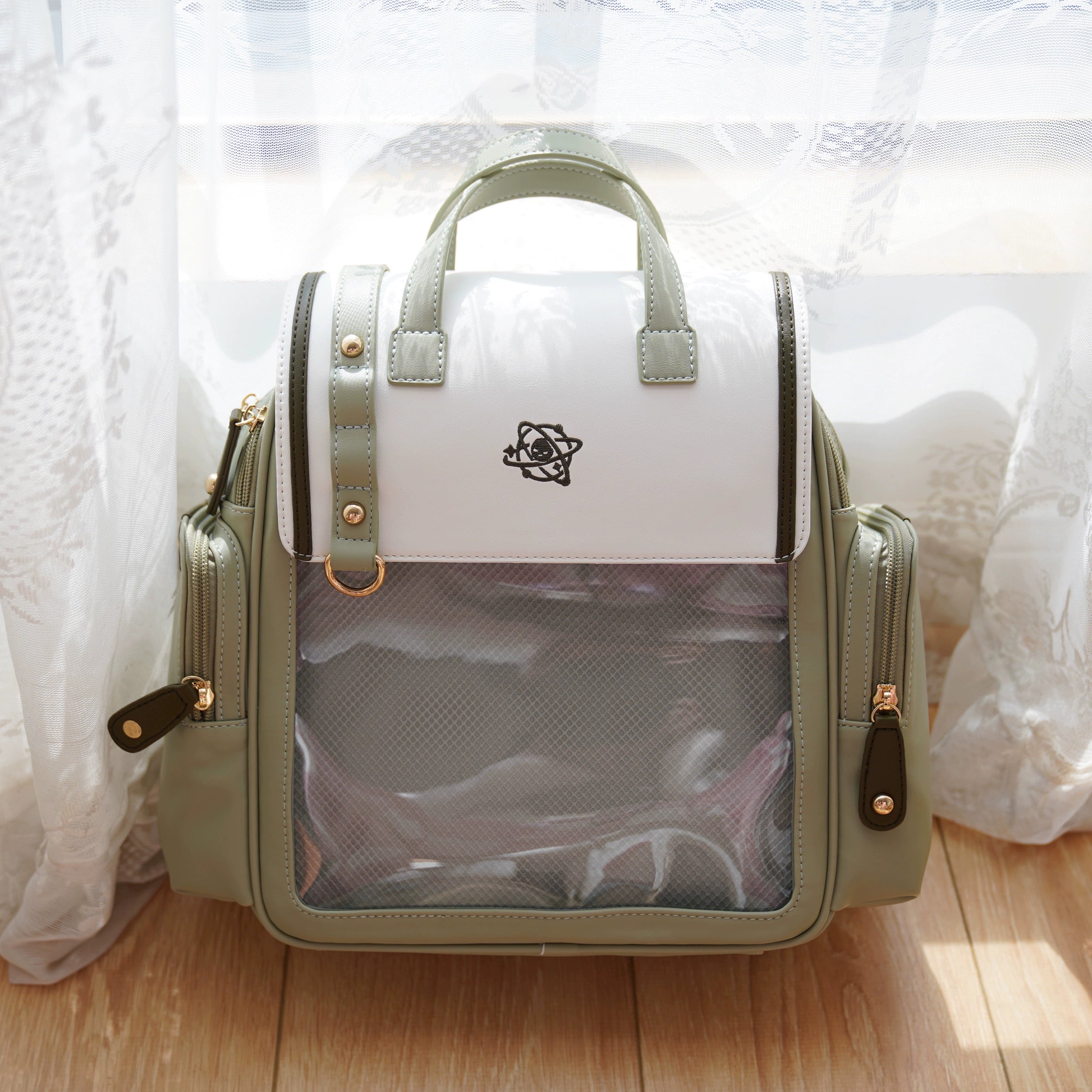Green and white Jirai Kei itabag backpack flat frontal view with transparent display panel on wooden floor background