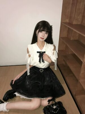 Model sitting wearing Seiso Kei blouse and jacquard butterfly skirt showing heart-shaped rhinestone waist detail and skirt silhouette