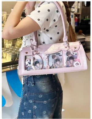 Pink vintage baguette itabag with transparent display window showing anime character badges in indoor cafe setting, rear angle view