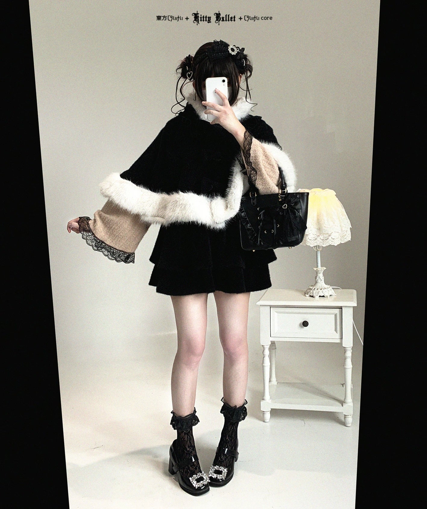 Black and white cat-ear hooded cape worn by model in coordinate setting, featuring contrasting fuzzy trim and detachable front bow styling