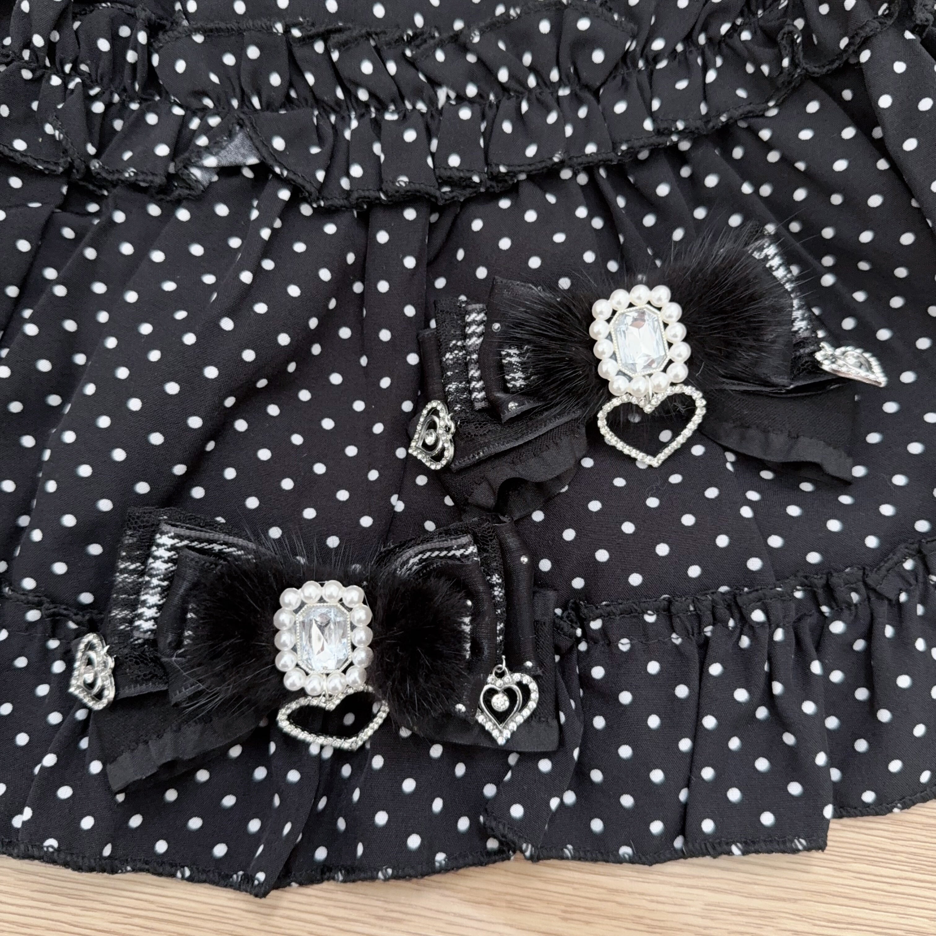 Black fluffy plush Jirai Kei bow hair clips with large central rhinestones and sparkly heart pendants on wooden tabletop styling