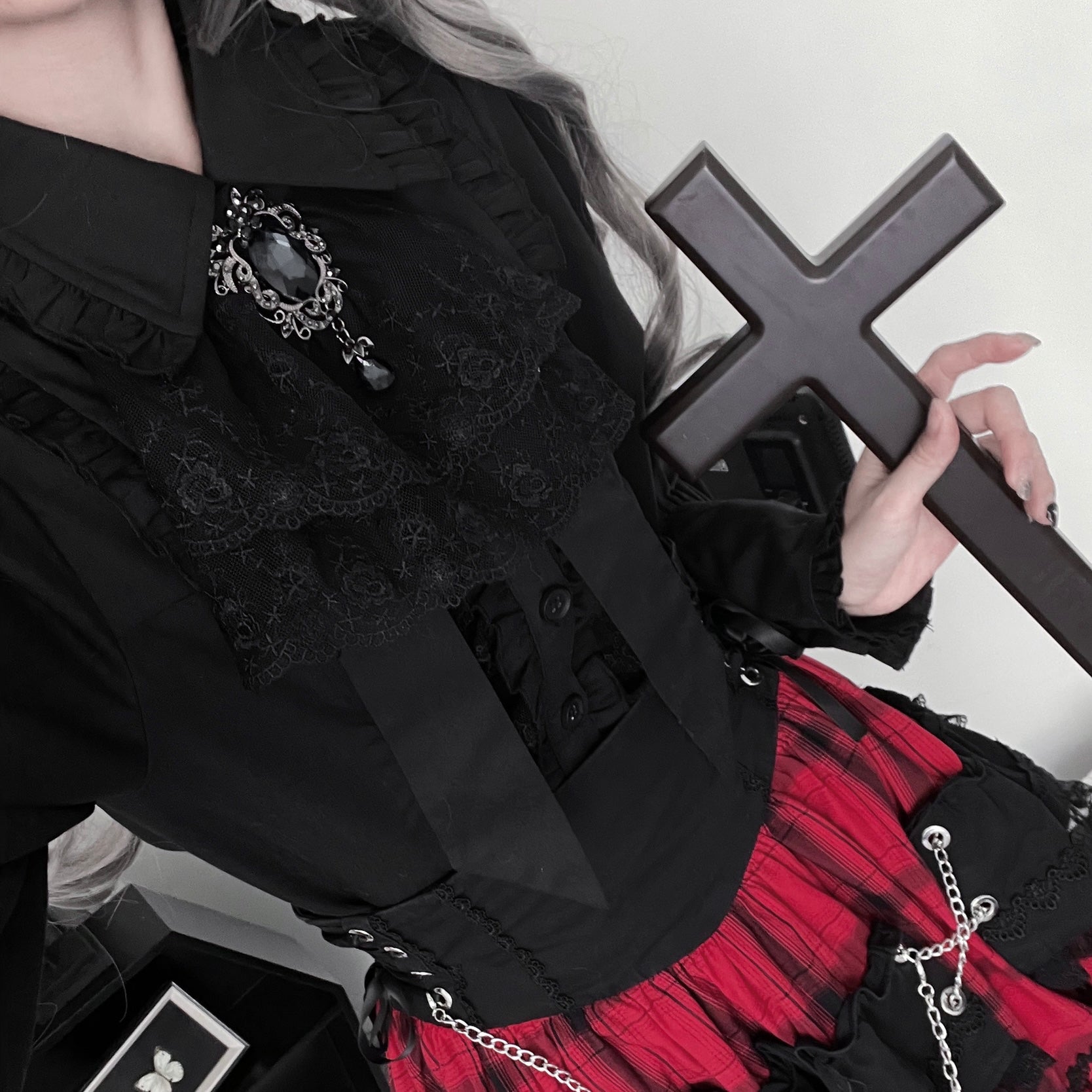 Close-up detail of black Jirai Kei blouse lace collar gem brooch and ruffled fabric texture