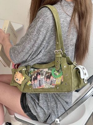 Army green Jirai Kei ita shoulder bag back side worn on sitting model indoors, studded hardware details, star window with pin collection display, plush pendant charm