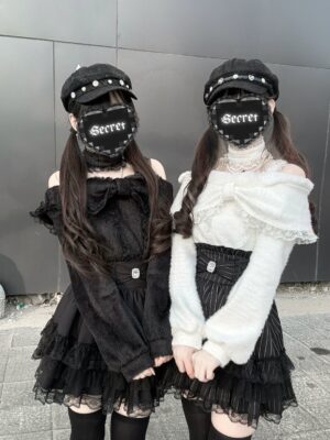 Off-shoulder plush fleece top with ruffle skirt worn by two Y2K goth models outdoors, featuring matching newsboy hats and street style aesthetic