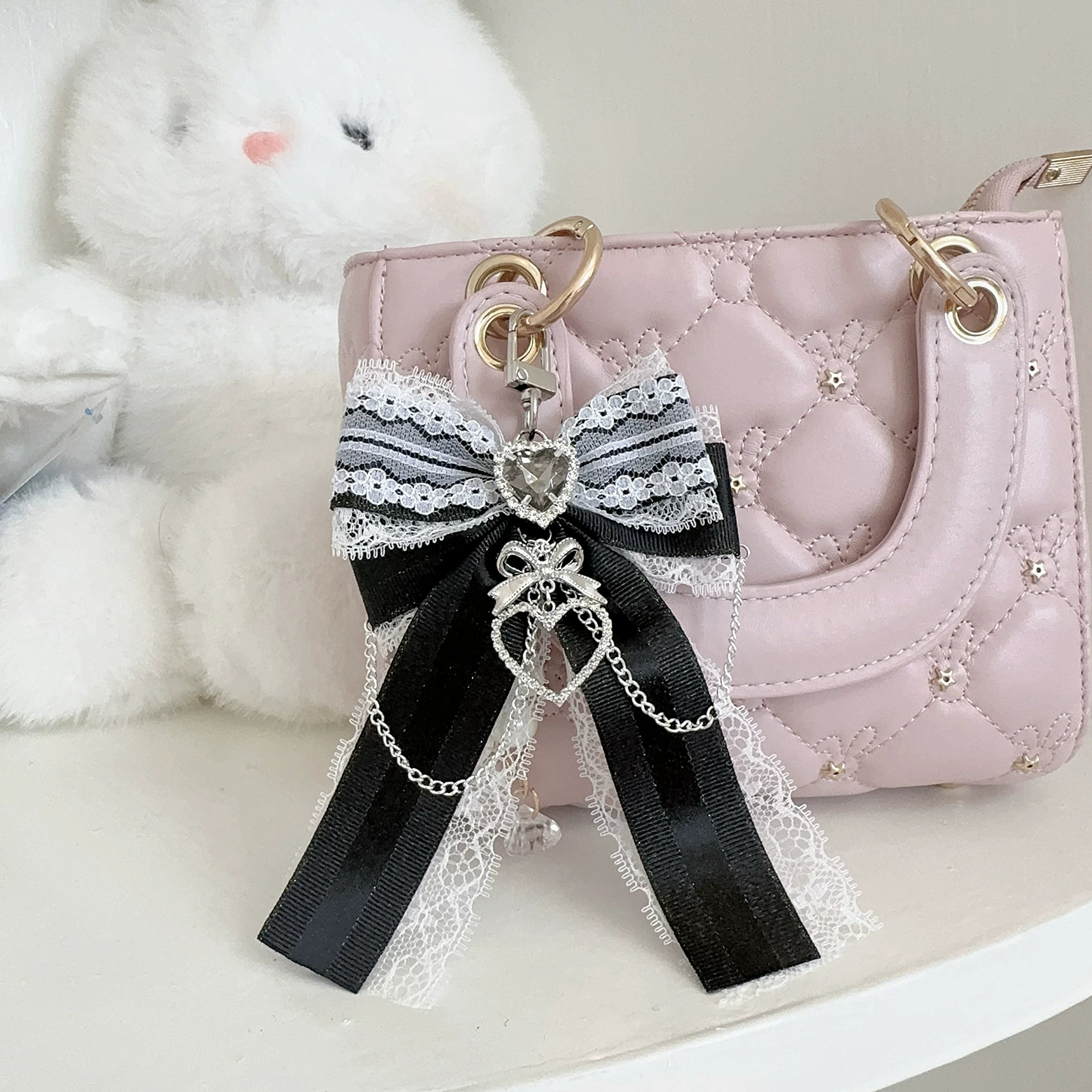 Black and white Ryousangata bow bag pendant with black satin bow and white lace trim on quilted handbag - close-up view of heart rhinestone detail for Jirai Kei aesthetic