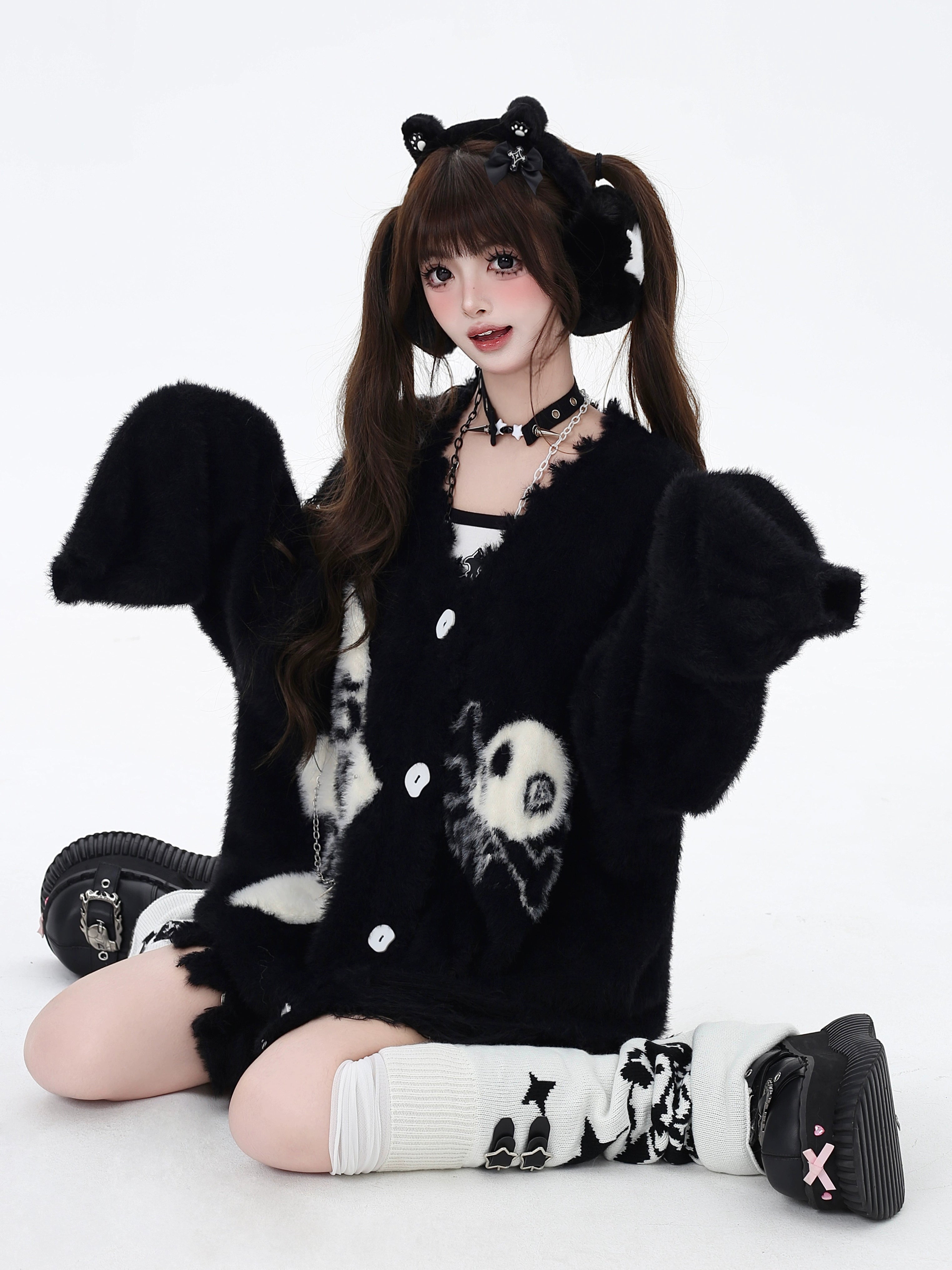 Black ear-hood Jirai Kei oversized cardigan with fluffy fuzzy fabric texture, skull and cross embroidered prints, sitting position showcase with twin-tail model styling