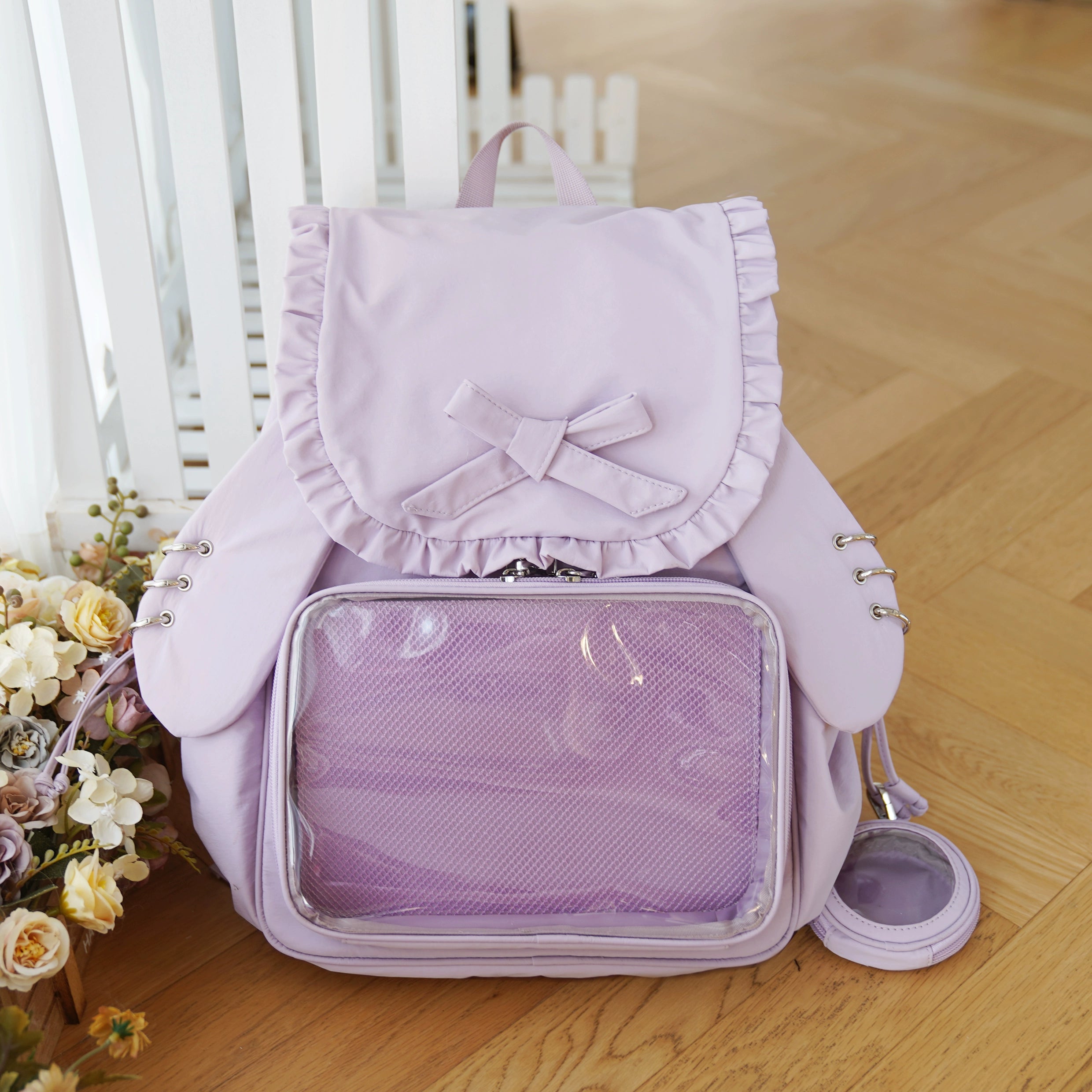 Lavender purple Jirai Kei bunny ear itabag backpack with large clear acrylic window for figure display, ruffled butterfly bow, and purple accessories