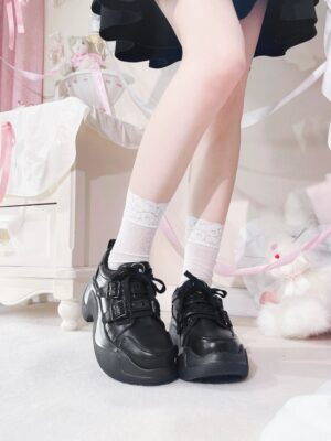 Black skull platform shoes detail view showing embossed skull logo on tongue, dual buckle hardware, and matte leather upper texture