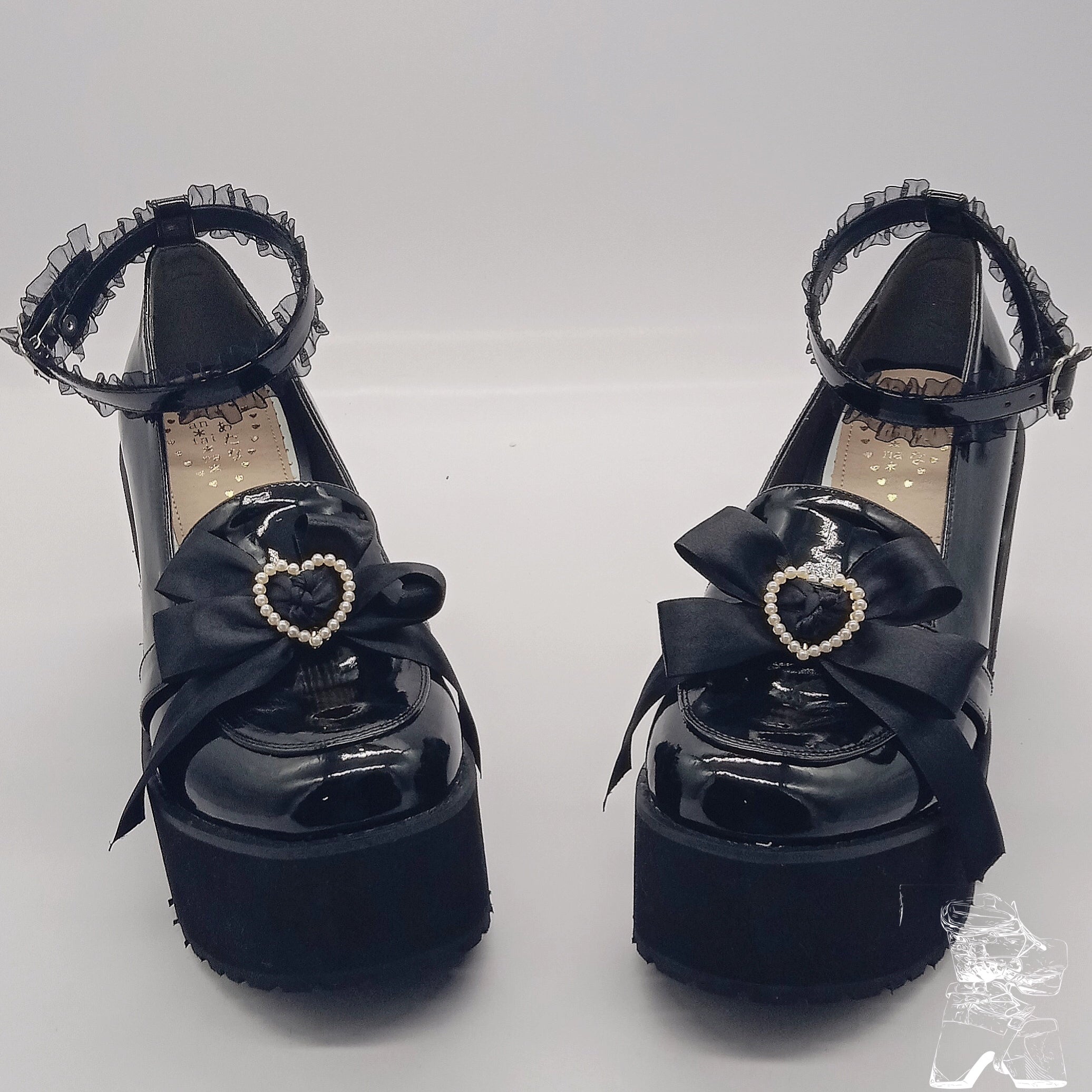 Black patent leather Jirai Kei platform shoes front view with lace ankle strap bow heart pearl ornament double shoe display