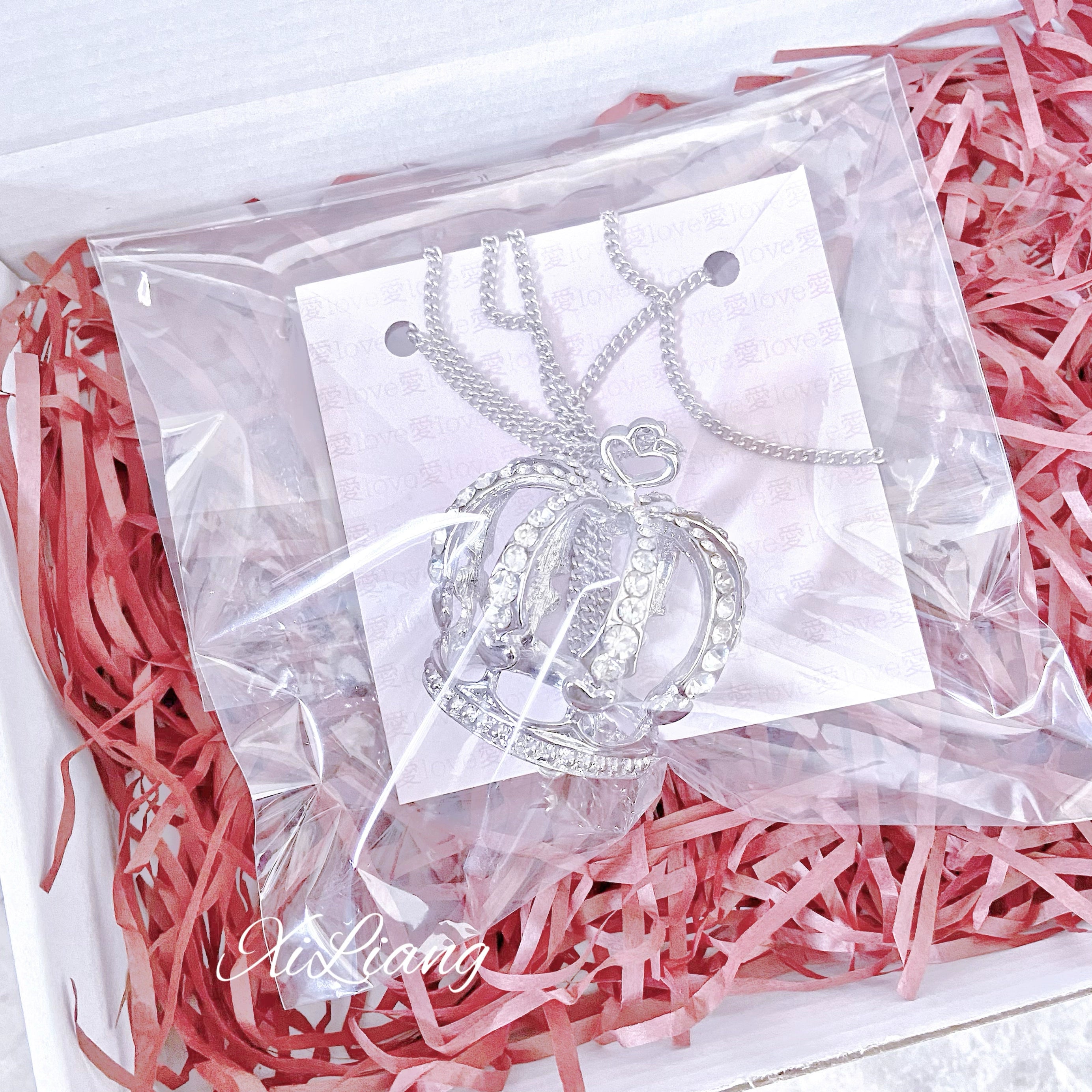 Packaged crown rhinestone necklaces displayed on card in luxury gift box with red shredded packing filler, silver crown pendant jewelry presentation