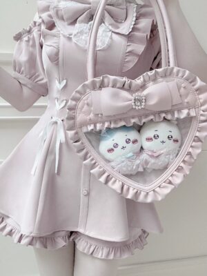 Pink heart-shaped itabag worn on model in matching pink ruffled lolita dress, side view showing clear window with plush toy collectibles