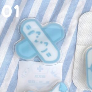 Tenshi Kaiwai cross bandage acrylic hair clip with smiling face design on blue-striped fabric background with medical prescription card