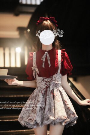 Burgundy Jirai Kei salopette dress front three-quarter view vintage stairwell setting with model holding dessert tray jacquard floral bubble hem