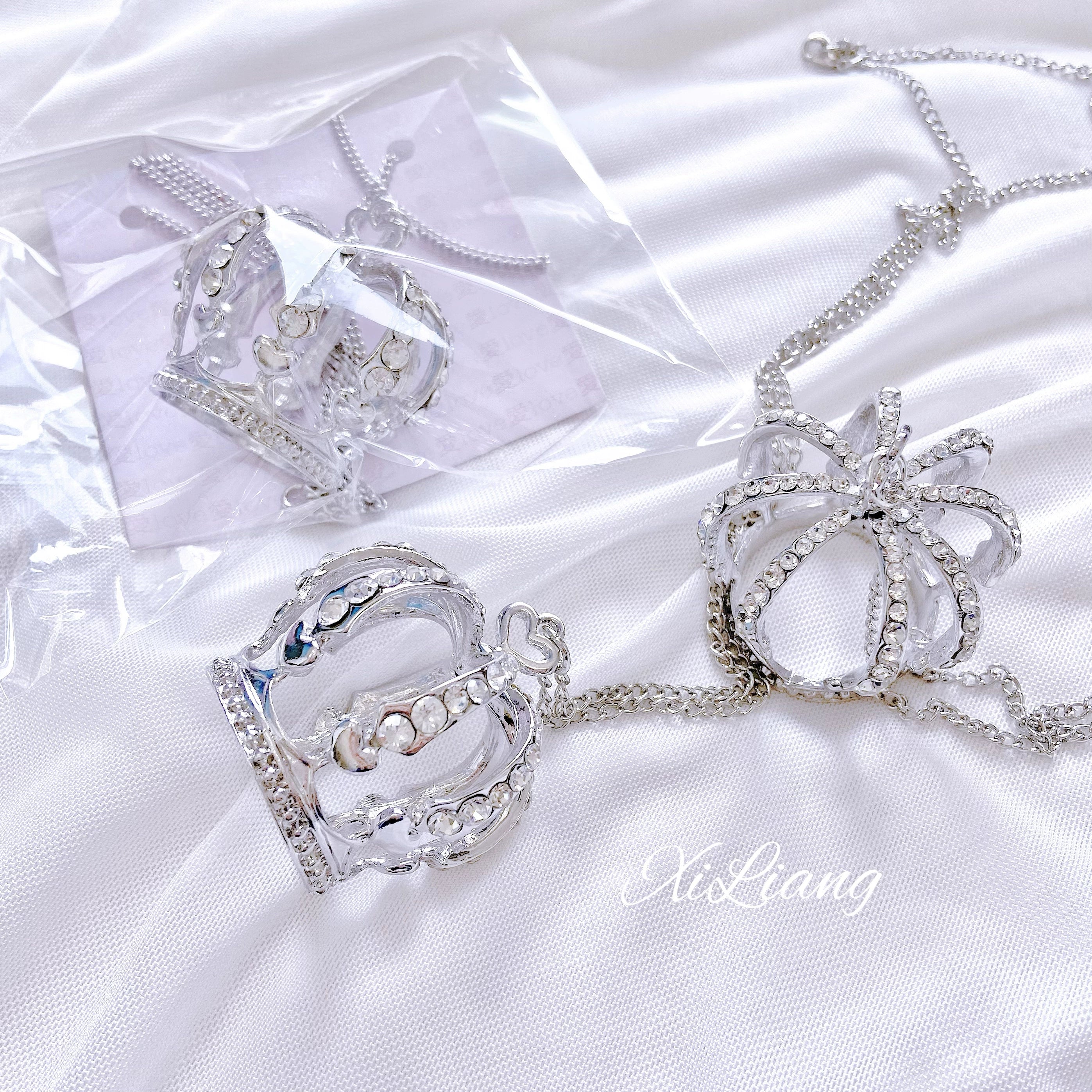 Crown rhinestone necklace and matching ring set in plastic packaging on white satin, silver hollow crown designs with rhinestone embellishments attached to metal chains