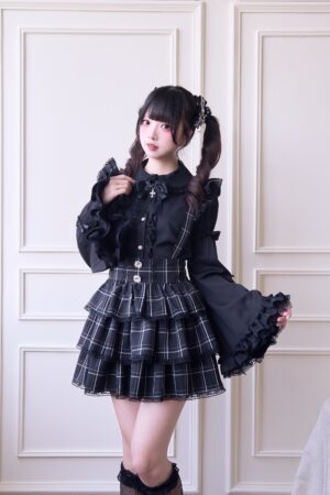 Black plaid Jirai Kei suspender skirt with detachable straps front view full body shot with ruffled black blouse and tiered plaid mini skirt
