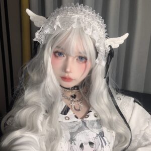 Jirai Kei angel wing headdress on model with long silver-white curly hair, front portrait showing intricate white lace trim and sculptural angel wing design