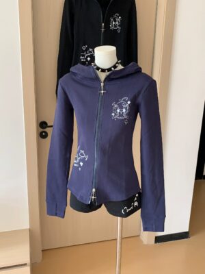 Navy blue zip-up hooded Jirai Kei jacket with white graphic anime prints and cross metal zipper, front view display on mannequin, slim fitted silhouette for Jirai aesthetic