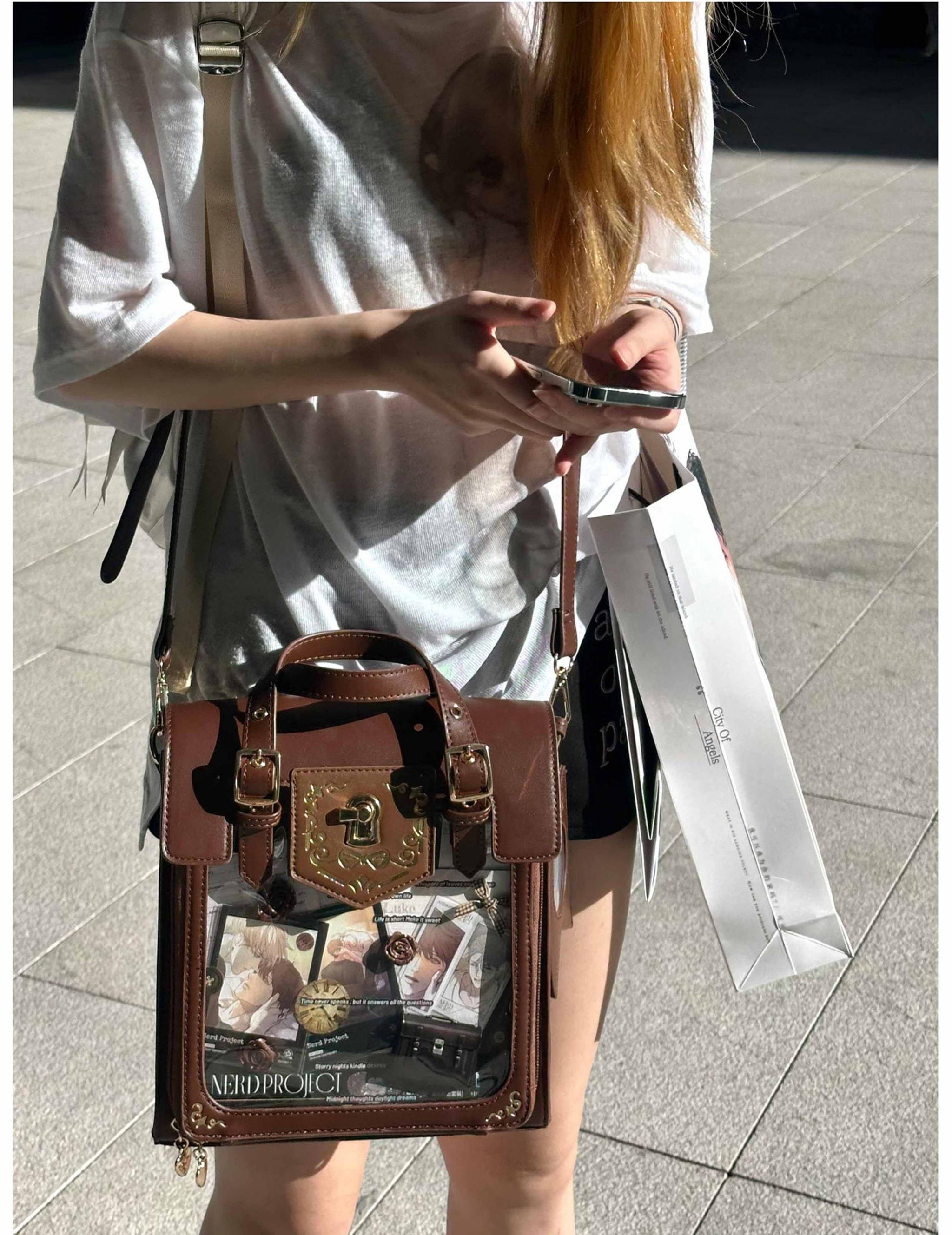 Two-tone dark brown and cream vintage Jirai Kei ita satchel bag with gold lock decoration and clear display window, back three-quarter view worn by female model in outdoor street setting
