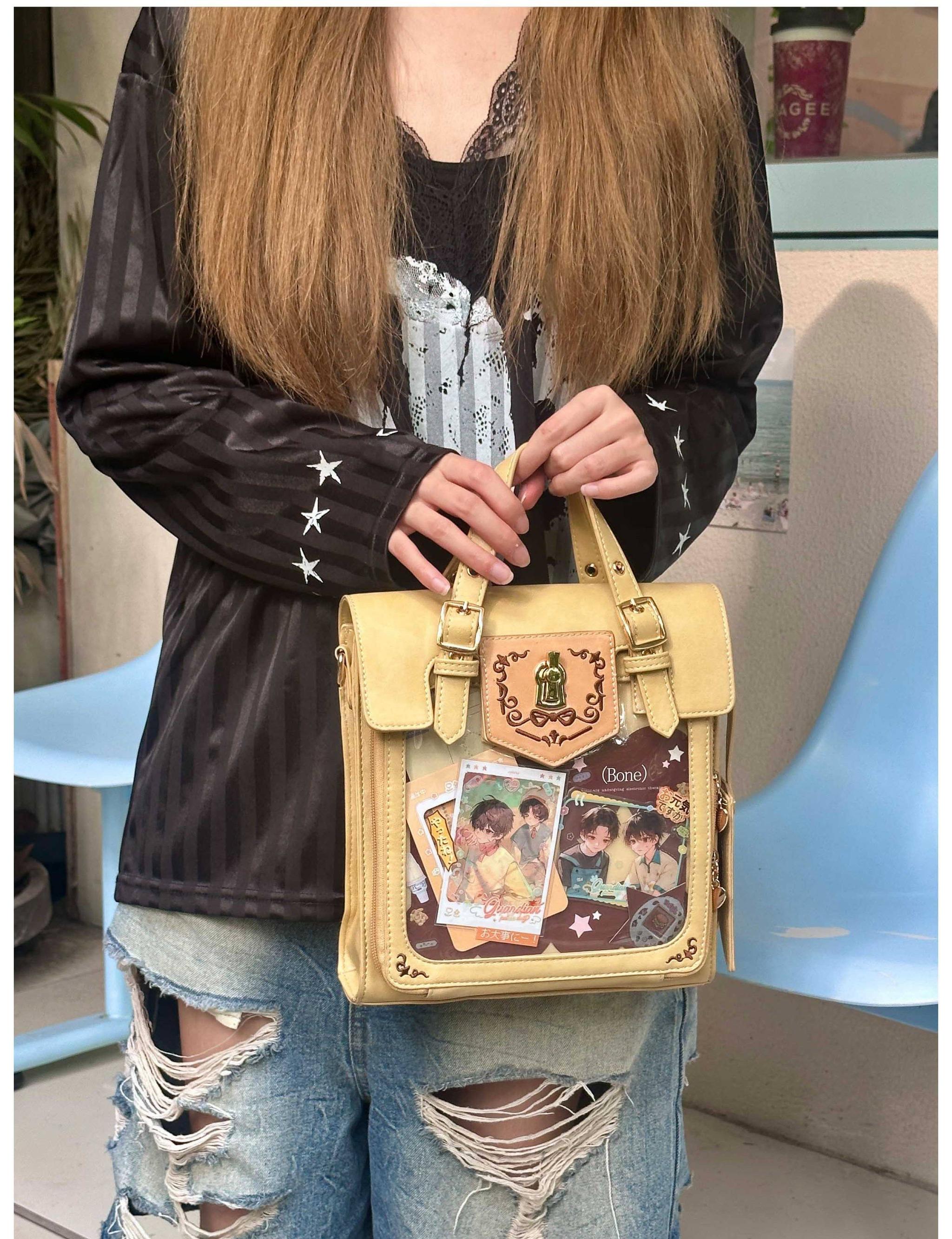 Beige vintage embroidered Jirai Kei ita satchel bag with clear display window filled with colorful anime prints and decorative patches, worn by model in casual ripped jeans cafe aesthetic