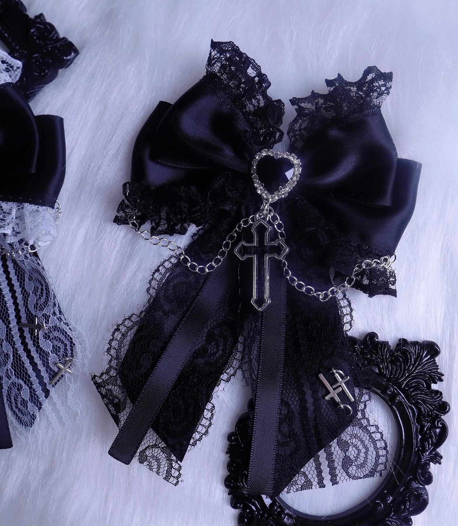 Black satin lace bow hair clip flat lay view showing silver cross pendant and heart-shaped rhinestone metal charms with hanging chain details