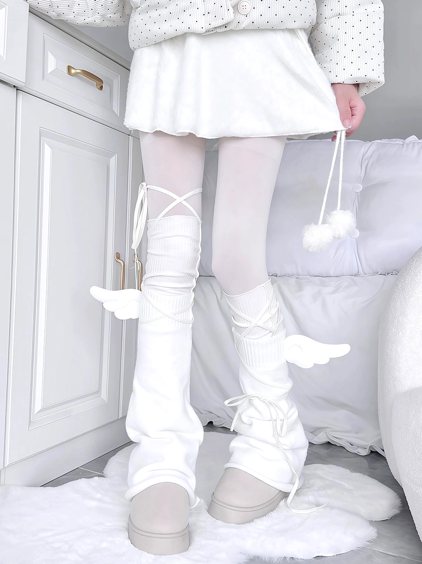 Angel wing cross-lace white leg warmers with delicate wing decorations crisscross front ties paired with white tights beige platform shoes bedroom interior low-angle front view