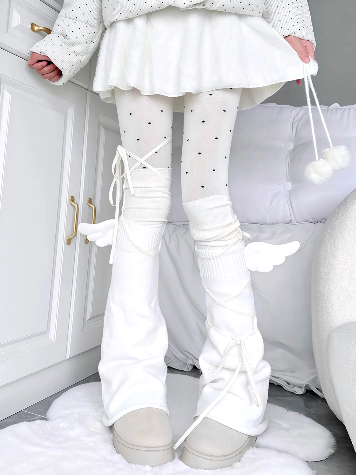 Angel wing cross-lace leg warmers with white knitted fabric and wing accents paired with black polka dot tights crisscross lacing detail beige platform shoes bedroom interior complete outfit