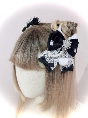 Black and white Ryousangata snowflake rhinestone ribbon bow hair clip with lace and fuzzy pom-pom details, side rear headwear view on mannequin