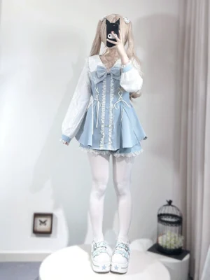Baby blue Jirai Kei two-piece dress set with lace trims and big front bow worn by blonde model with twin tails in mirror selfie view