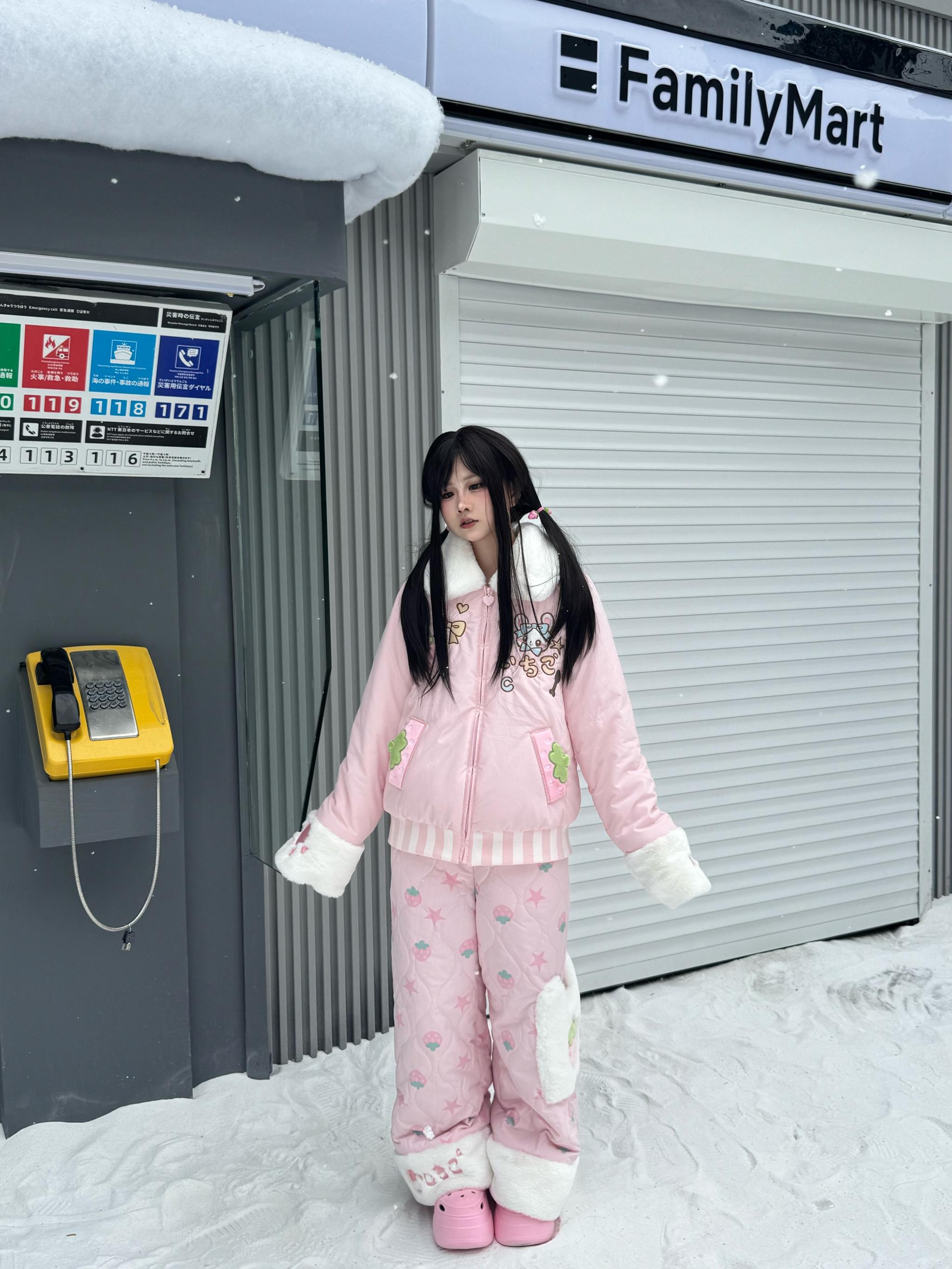 Complete front full-body view of strawberry Jirai Kei quilted winter two-piece set featuring fuzzy-cuffed zip jacket matching printed pants and pink shoes in front of snowy Japanese storefront