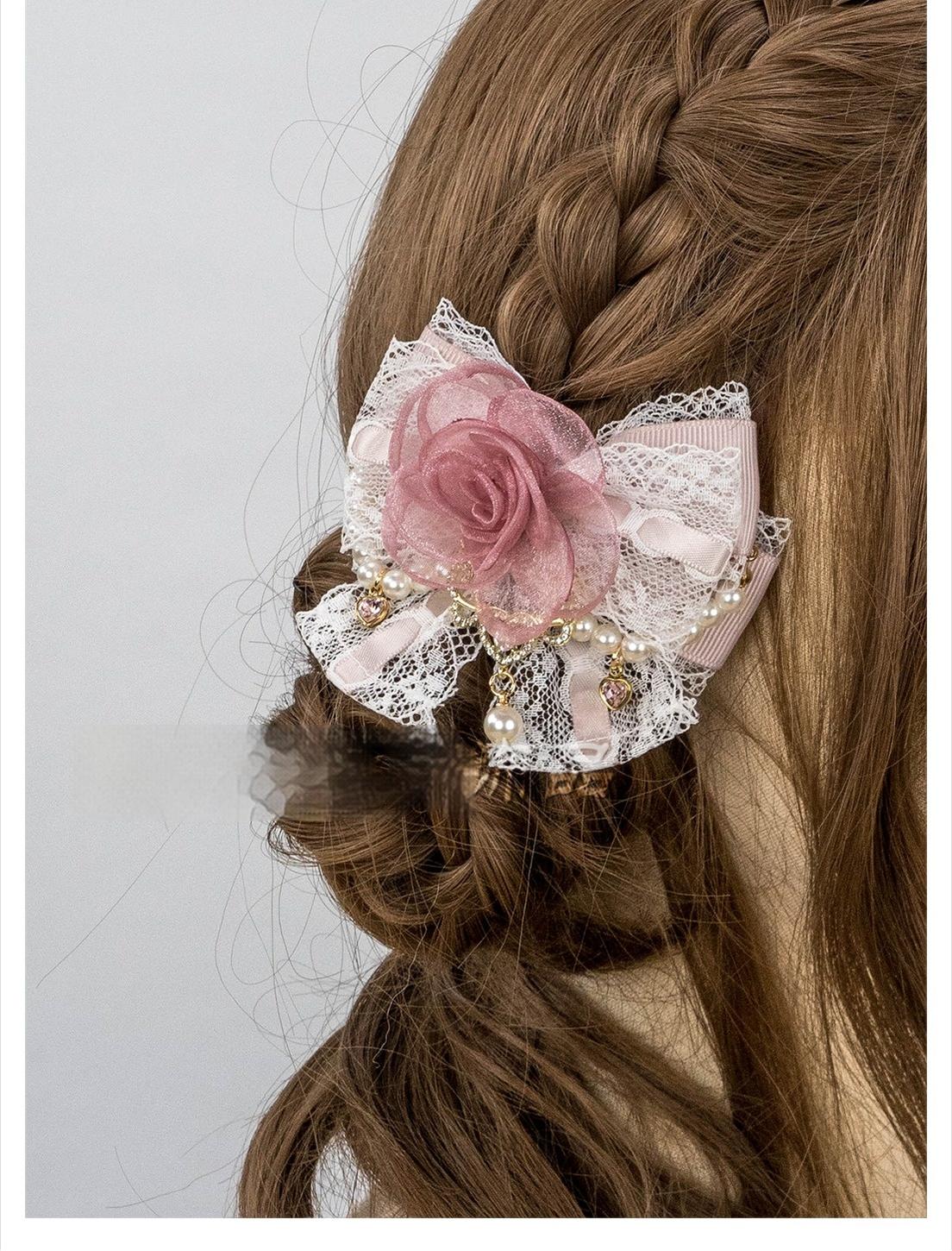 Close-up back view of pink rose hair clip with fabric rose lace bow and hanging pearl details on braided hair