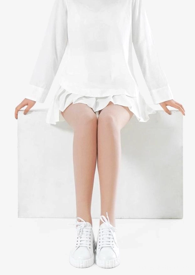 Front seated leg shot showing beige velvet tights with white blouse and white sneakers - demonstrates sheer natural skin-like coverage and comfort for sitting