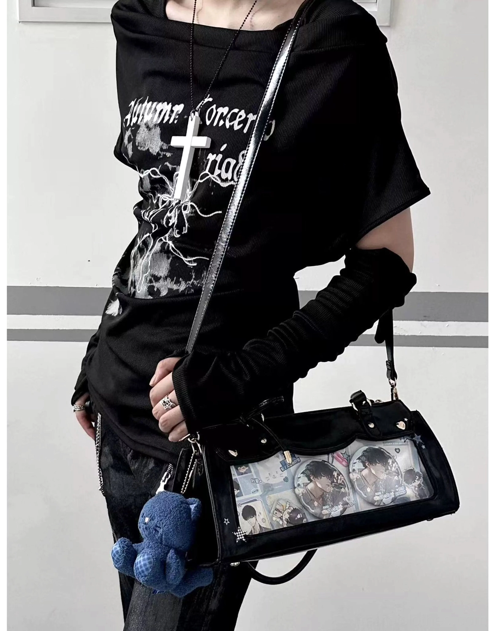 Black baguette itabag with detachable crossbody strap and blue plush charm, anime badge showcase simple indoor background