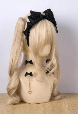 Black bow KC Jirai Kei hair clip with heart-chain dangles on blonde mannequin twin ponytails front view