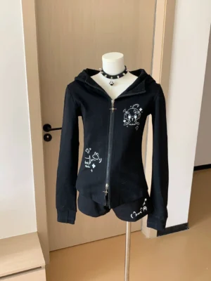 Black bunny ear hooded Jirai Kei jacket with white cartoon prints and dual-way metal zipper, front full view on dress mannequin, slim fit design perfect for alternative fashion