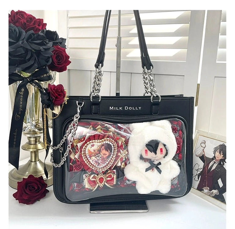 Black checkered ita bag flat lay with anime heart badge and plush doll decoration on floral desk with red roses
