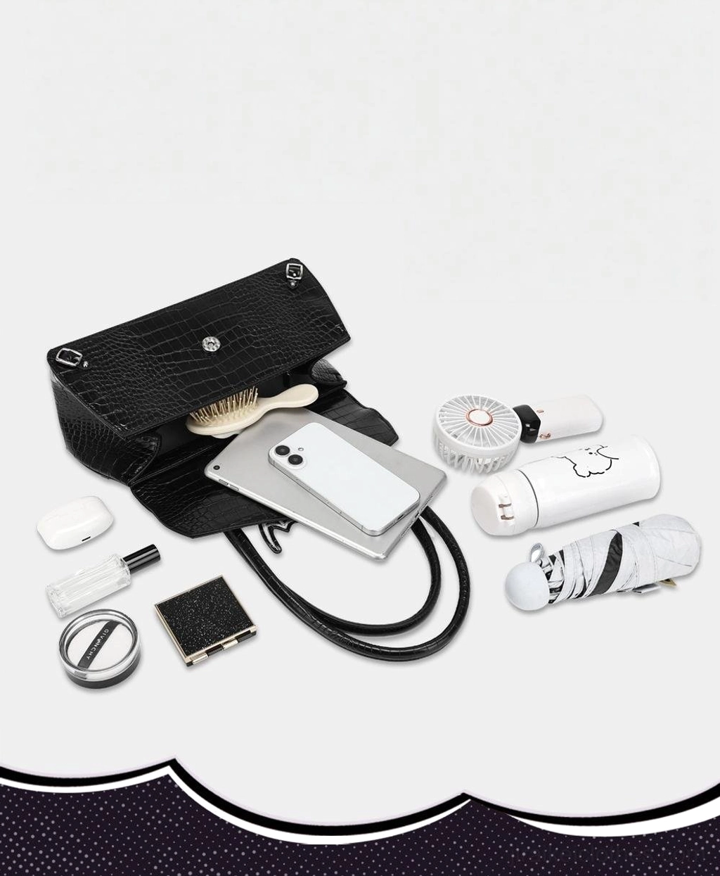 Open black croc texture handbag displaying interior capacity with cosmetics and electronics detachable shoulder strap on daily tabletop