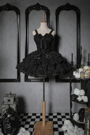 Black Gothic Lolita JSK dress front flat lay view showcasing spaghetti straps corset bodice layered ruffled skirt vintage gothic interior styling