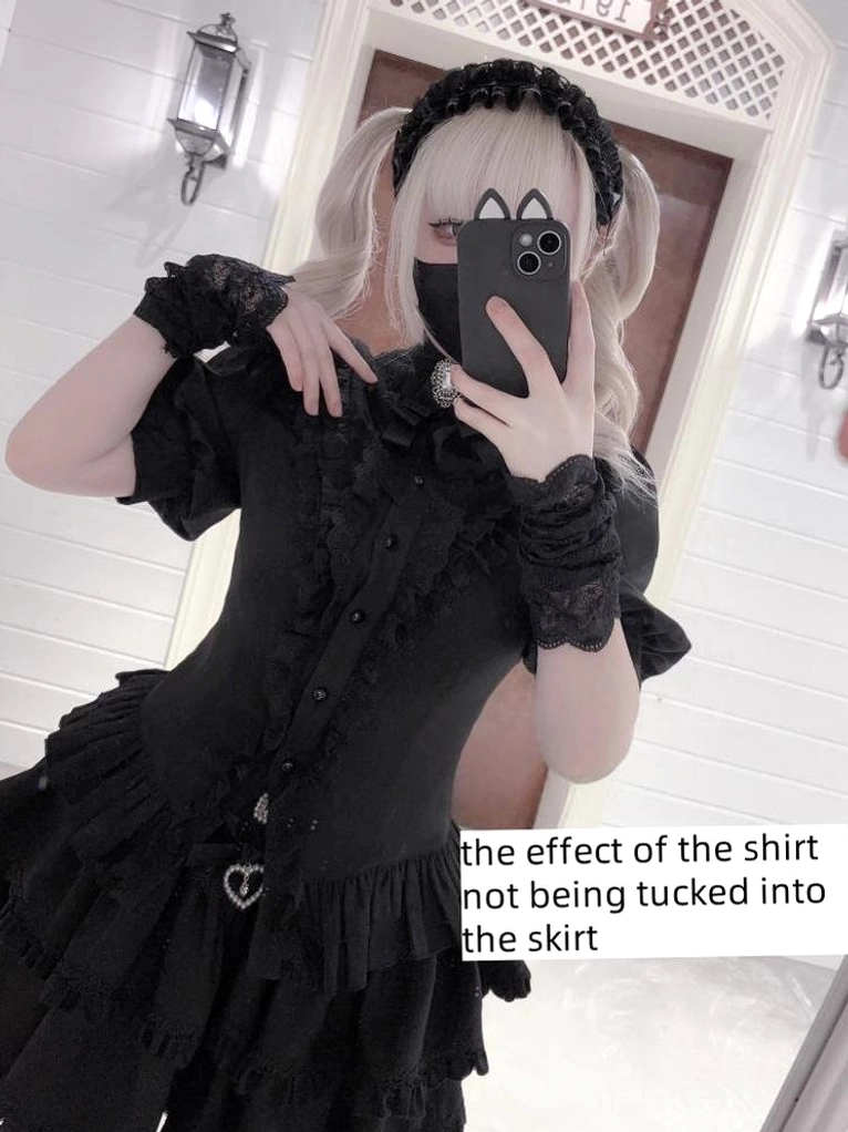 Black gothic lolita outfit mirror selfie front view showing ruffled lace collar, lace wrist cuffs, and heart-shaped skirt charm details in indoor home setting