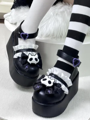 Black gothic platform Mary Jane shoes with purple heart ankle buckle and removable cat skeleton bow side angle view on white fur