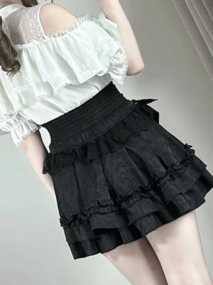 Black jacquard jirai kei mini skirt with elastic smocked waist and tiered ruffled hem, side profile view in indoor corridor setting