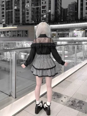 Black Jirai Kei blouse back view showcasing sheer lace shoulder panels and ruffled design details, paired with tiered gingham skirt