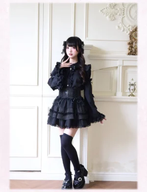 All-black gothic Jirai Kei outfit featuring long bishop sleeves with dramatic ruffles and structured black tiered skirt on vintage interior