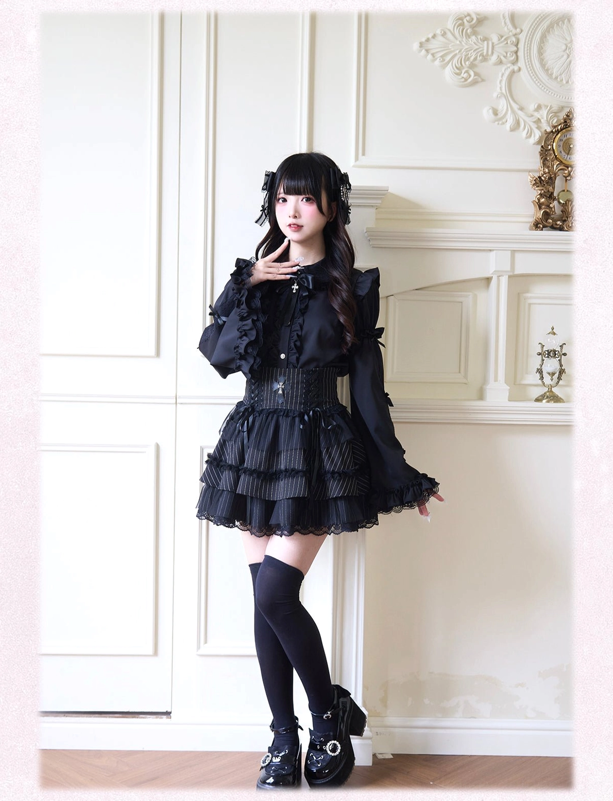 All-black gothic Jirai Kei outfit featuring long bishop sleeves with dramatic ruffles and structured black tiered skirt on vintage interior