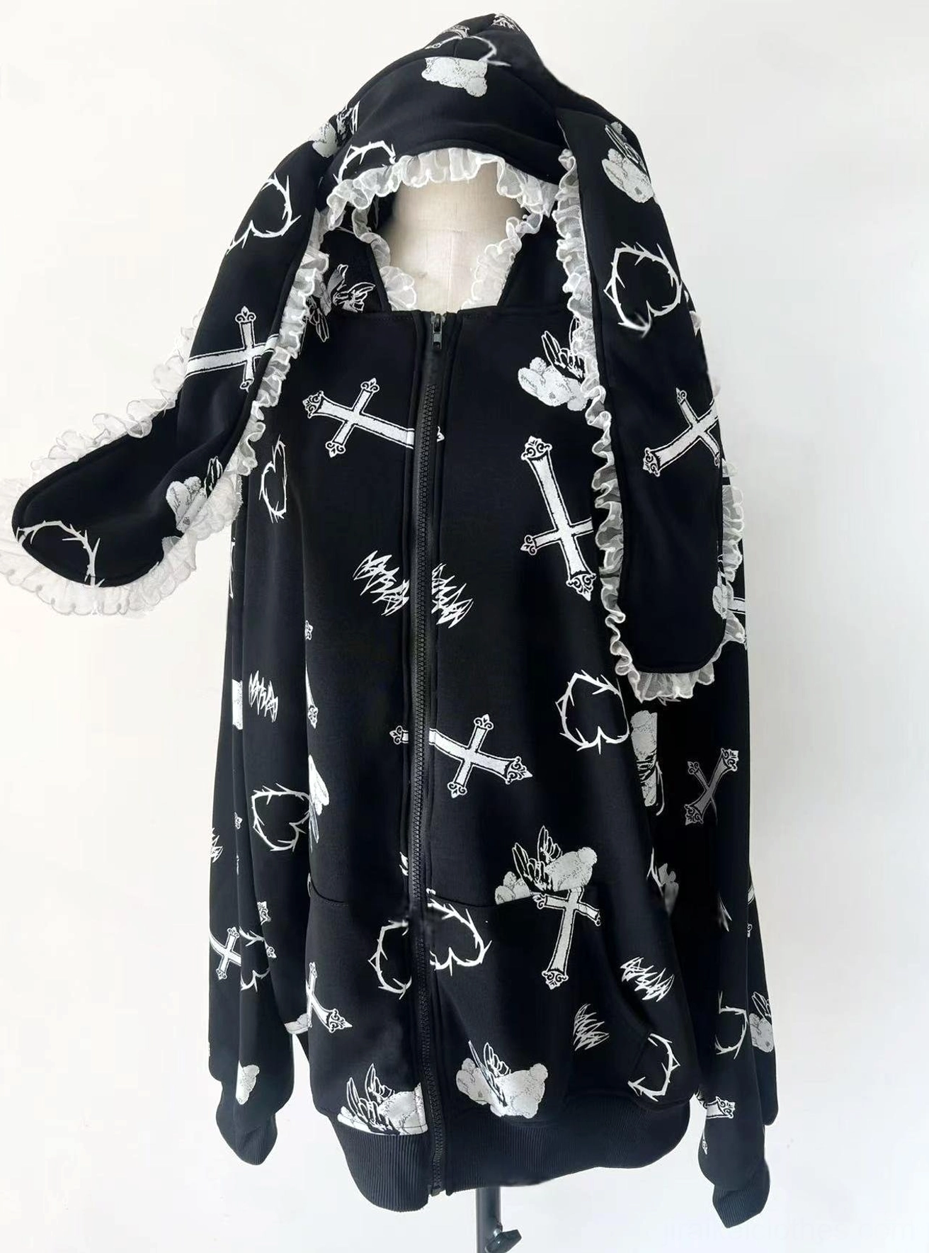 Black Jirai Kei bunny ear hoodie three-quarter front product view on studio white background, displaying lace-trimmed ears and cross print pattern details